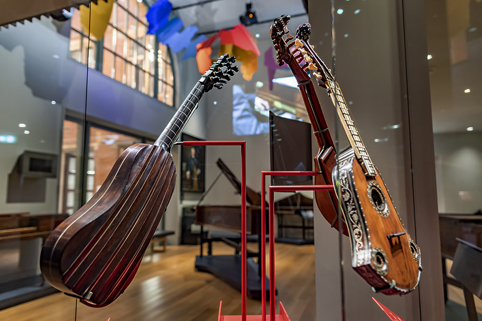 Historical guitars on display in a glass case in the 鶹Ƶ Museum.